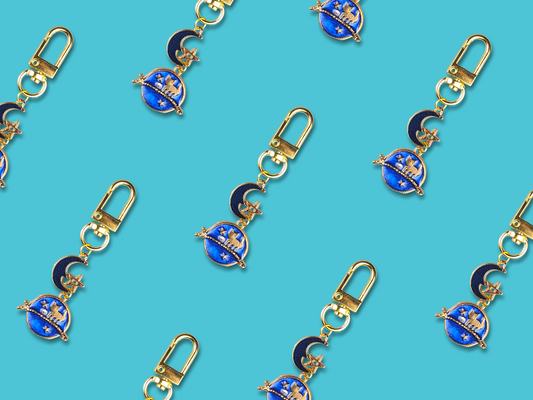 Gold-plated Moon Cats keychain with lobster claw clasp on a pastel background.