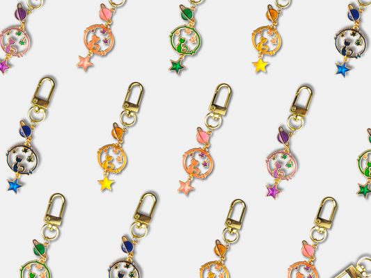 Colorful pastel Space Cat keychains with gold plated alloy and lobster claw clasps arranged on white background
