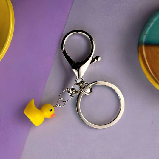 Mini duck keychain with yellow resin duck charm and stainless steel lobster clasp and key ring on purple background