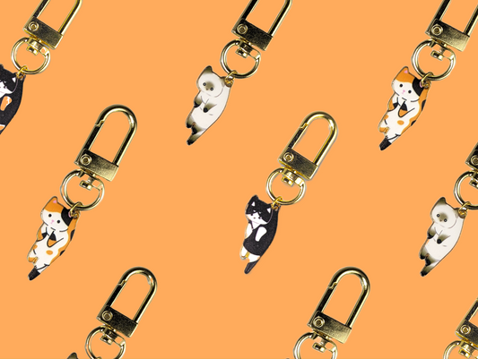 Mini Hang in there Cat keychains with gold-plated lobster claw clasps on orange background